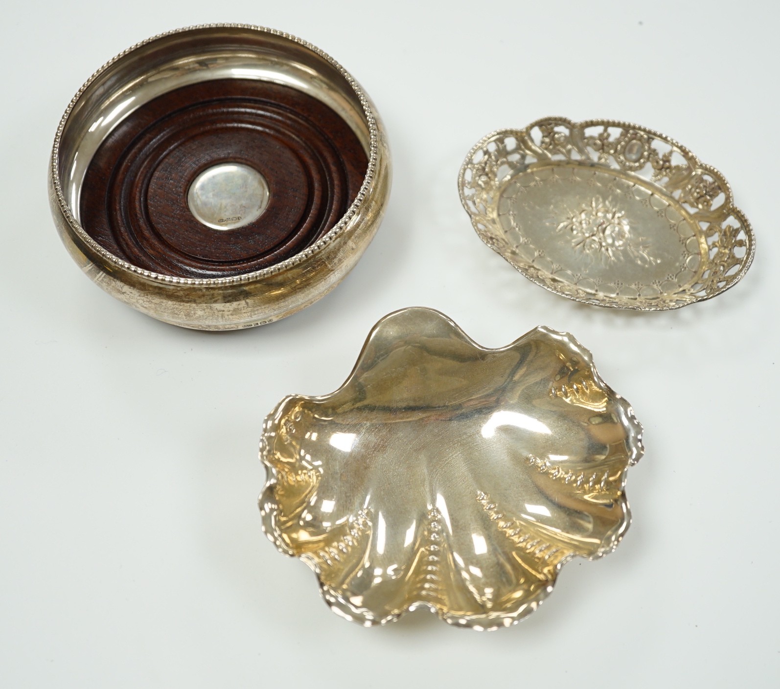 A modern silver mounted bottle coaster and two continental white metal small dishes.